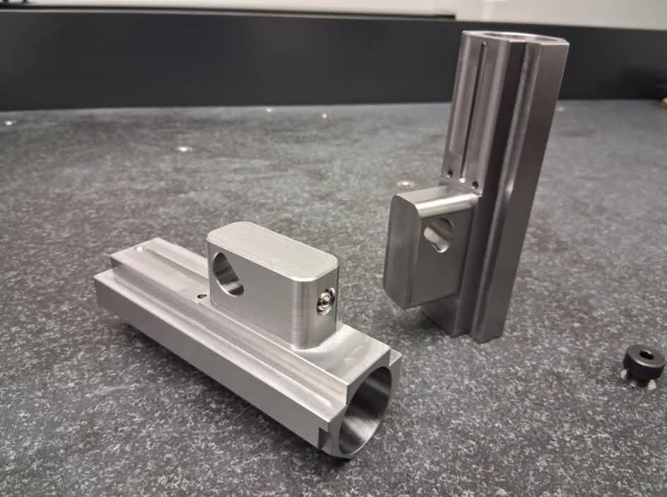Finished machined components standing on an inspection surface plate.