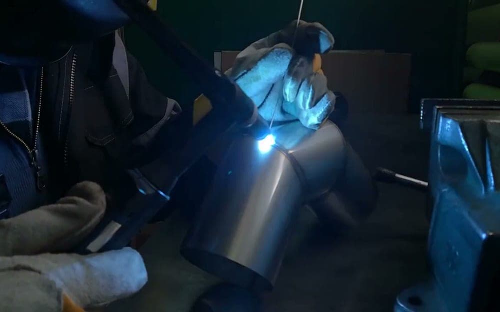 A TIG torch laying a bead along a stainless steel joint.